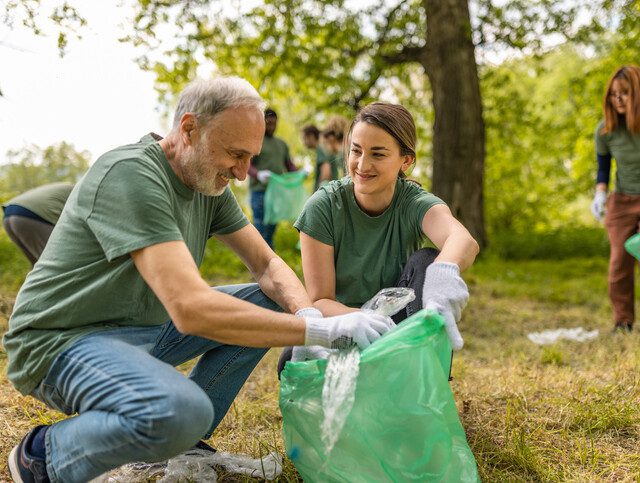 Older adult man and young woman collecting trash together in a park