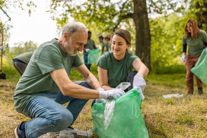 Older adult man and young woman collecting trash together in a park